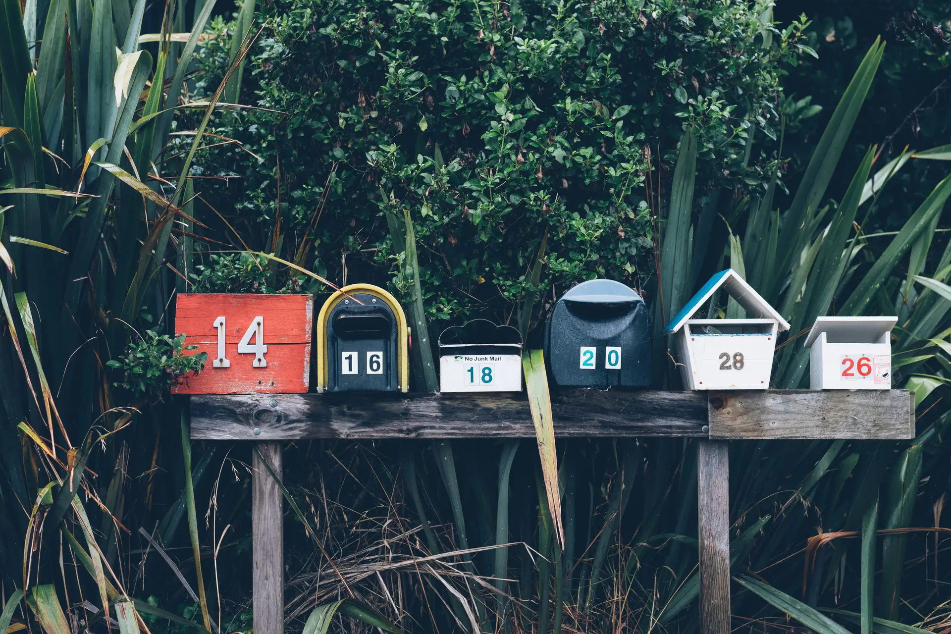 Assortment of post boxes of different color on a plant post.