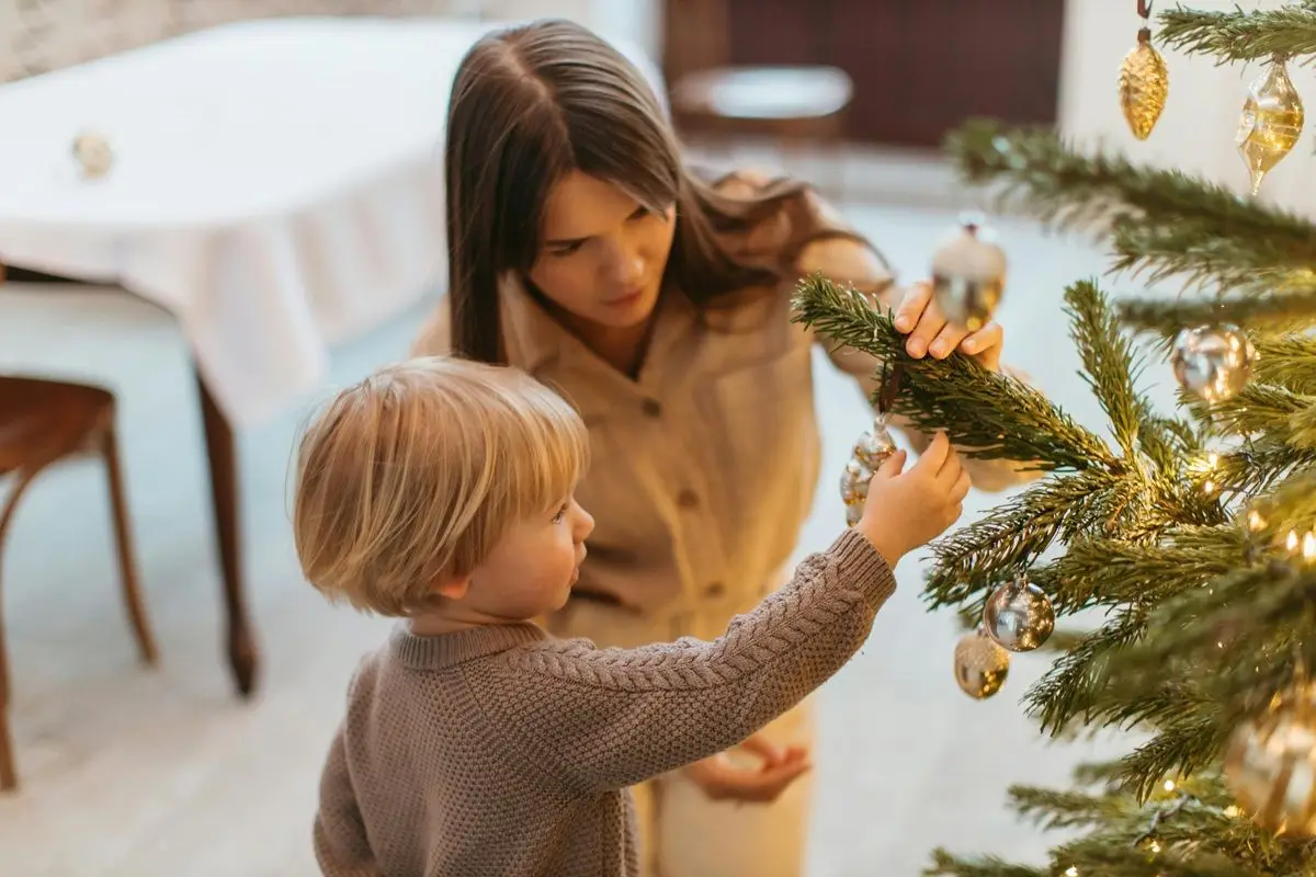 A child and mother decorating their Christmas tree.