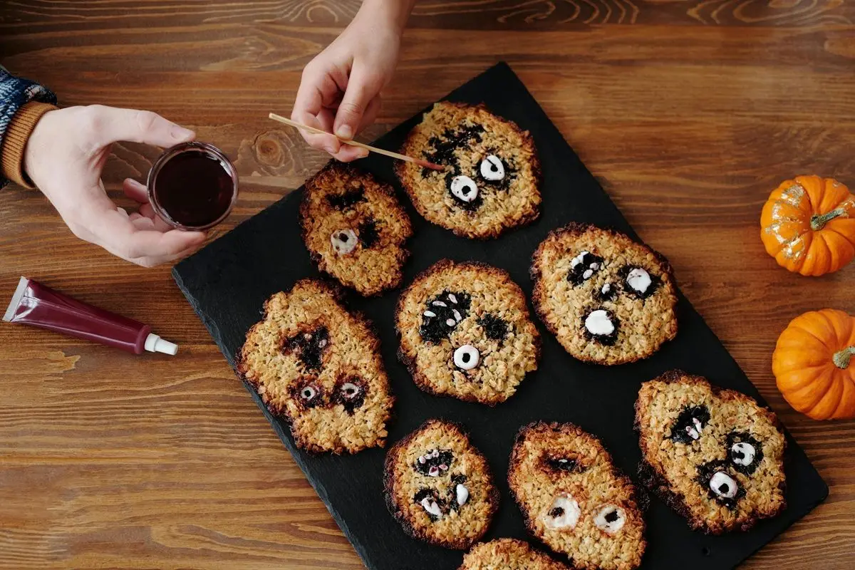 People creating scary cookies for halloween by drawing ghastly faces on the cookies.