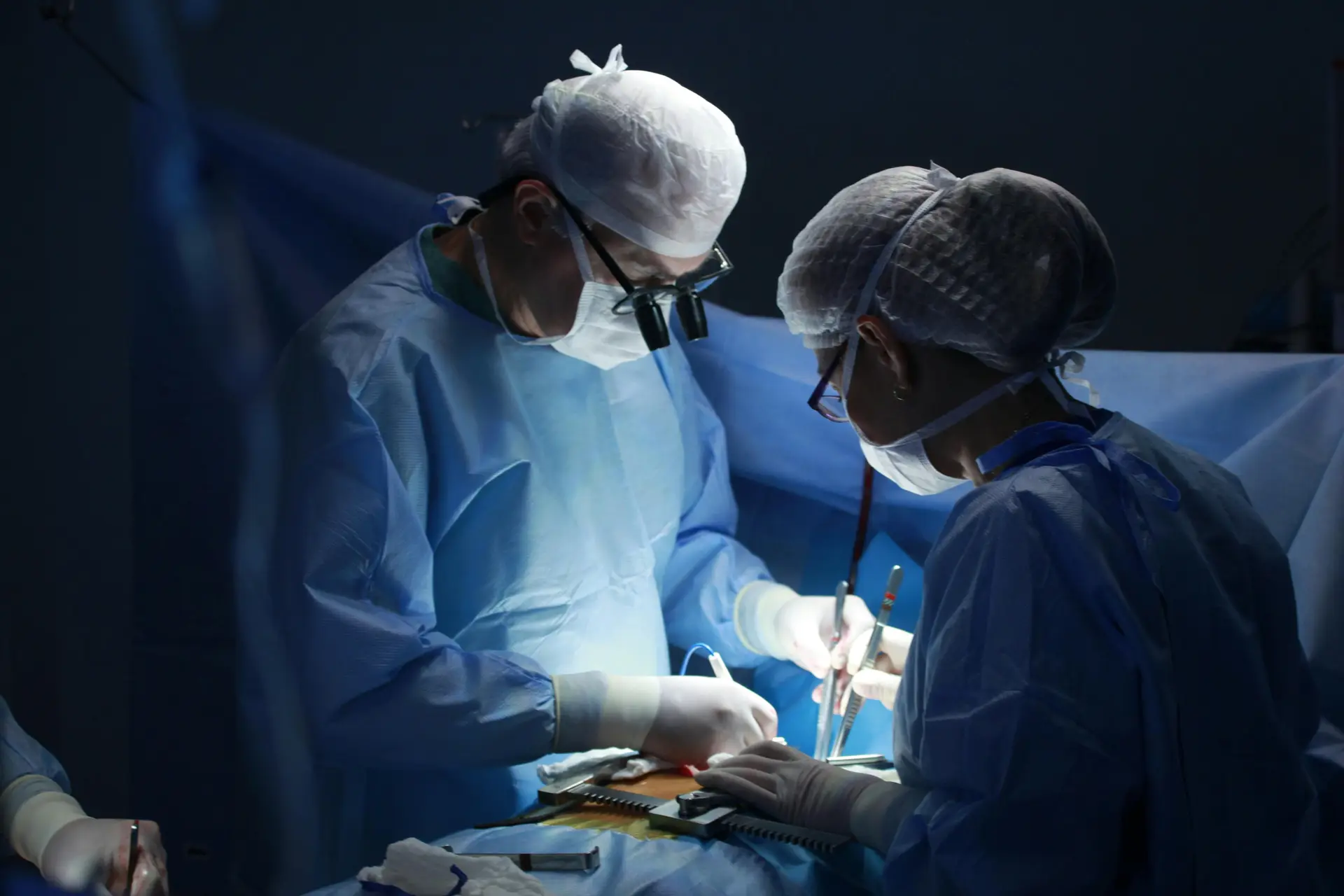 Physicians doing a surgery with their gowns and head covers on.