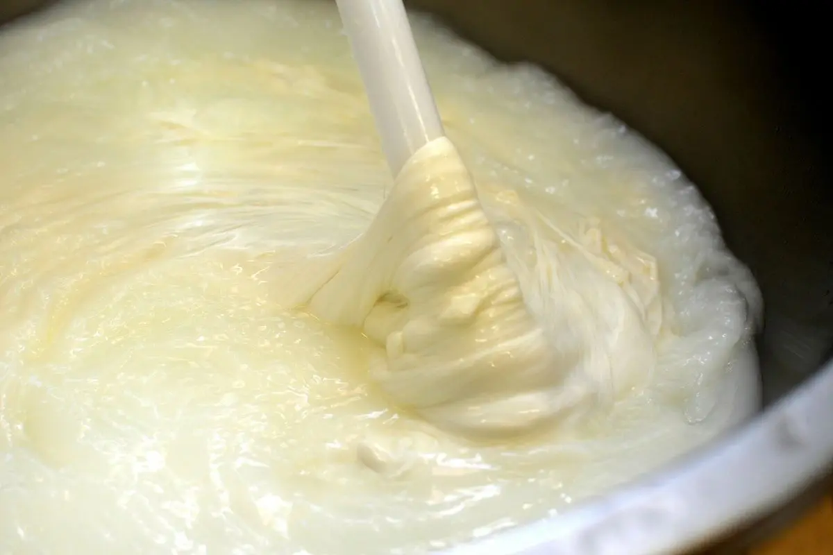 Milk being turned into cheese in a bowl.