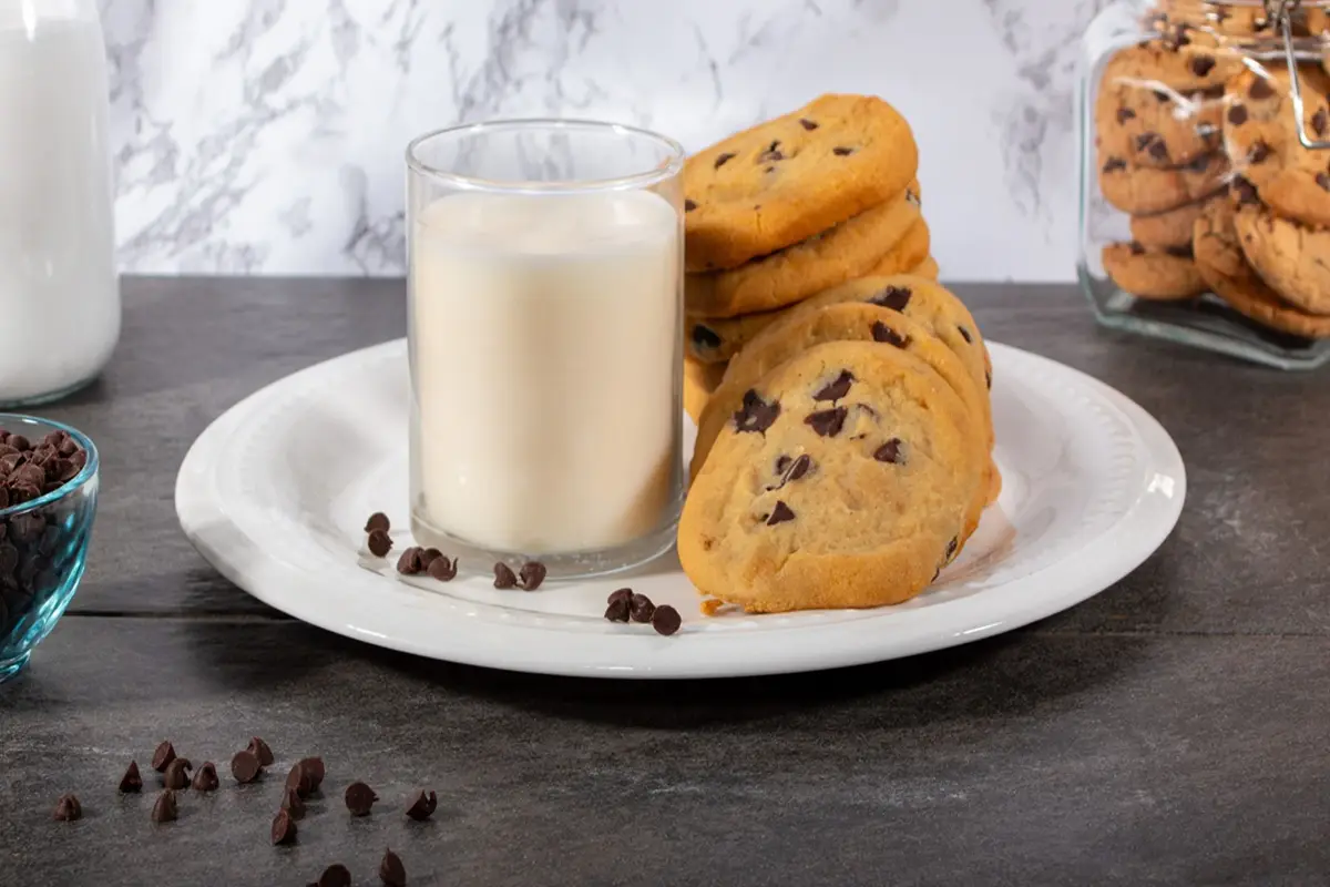 Tasty chocolate chip cookies paired with fresh milk on a white plate.
