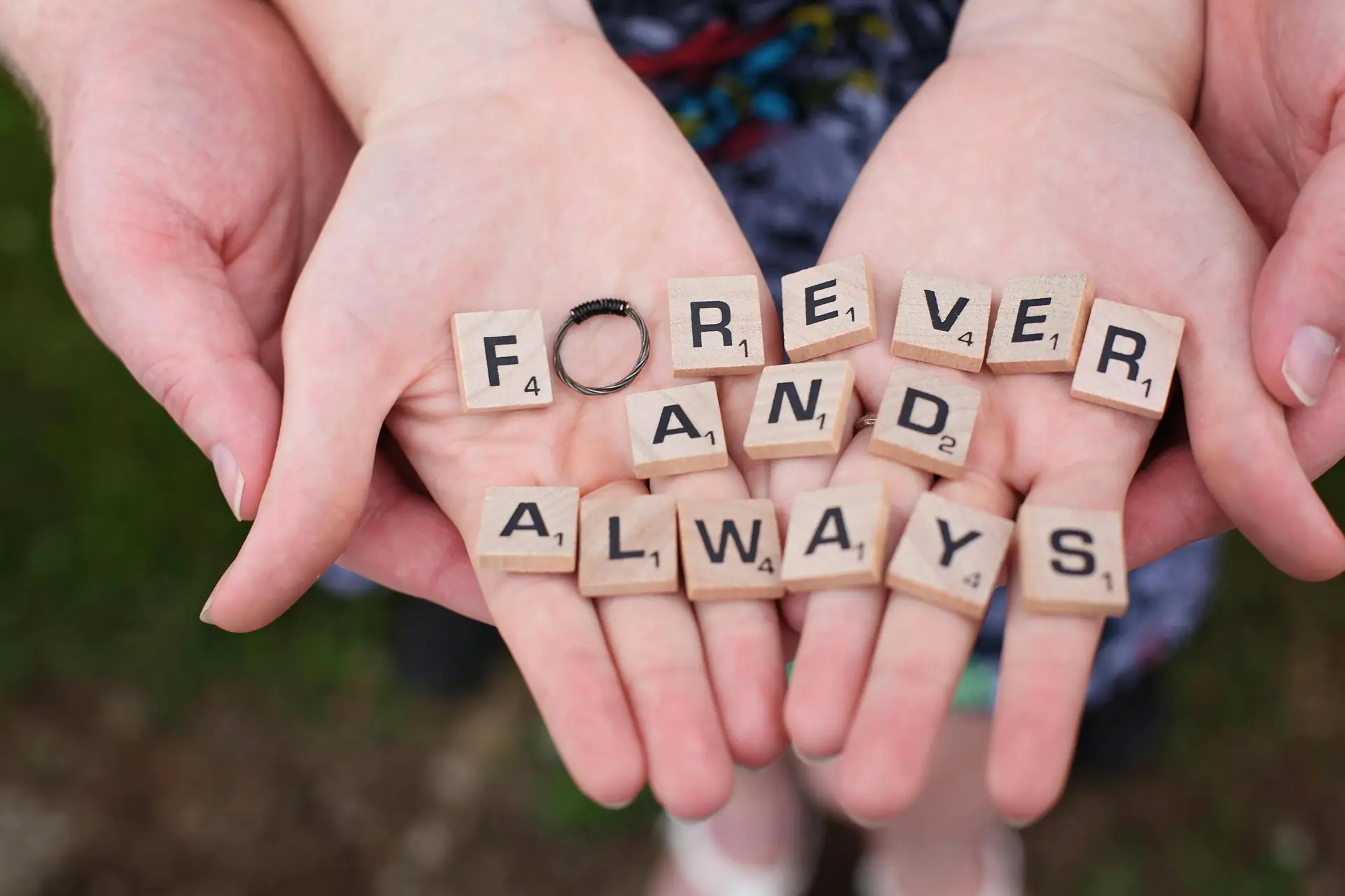Two hands on top of each other. On them, in alphabets blocks written is