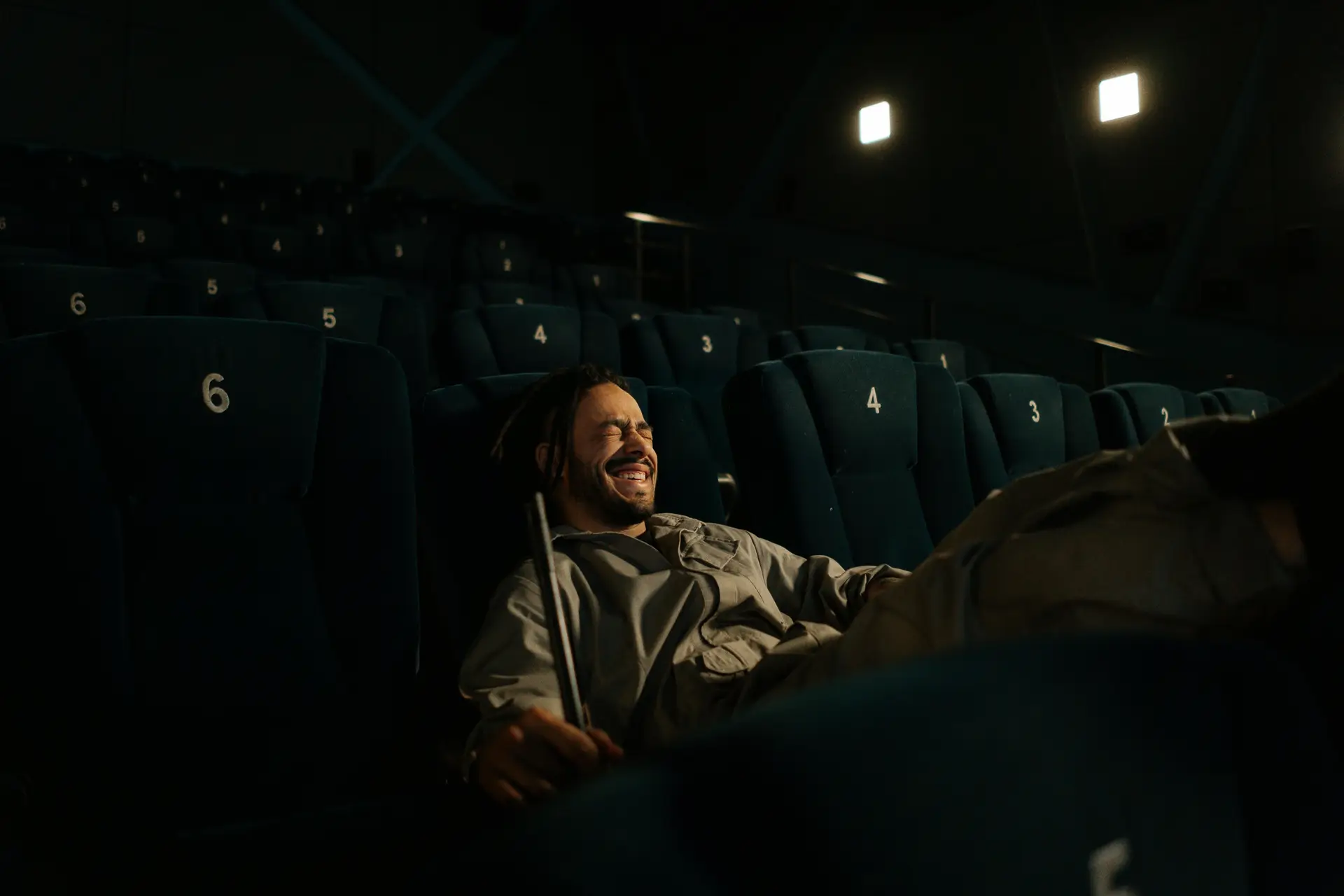 A person sitting in the movie theater laughing on his own.