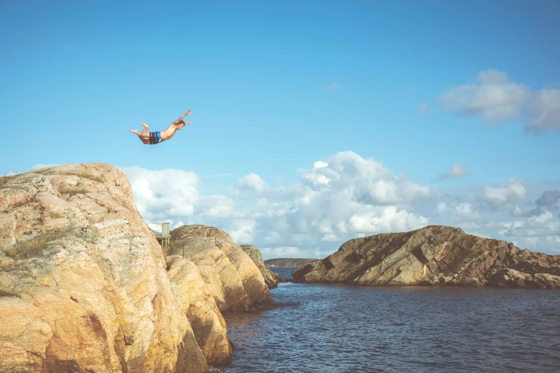 A man jumping from a cliff into a body of water.