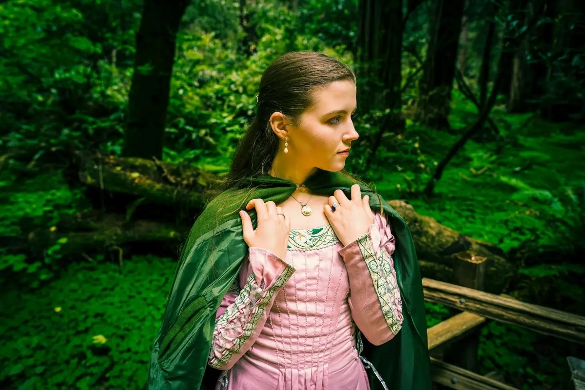 A person wearing a pink colored princess dress along with a green robe.