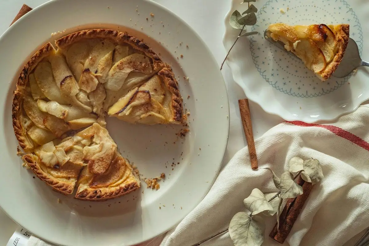 An american pie on a white ceramic plate along with another slice of pie.