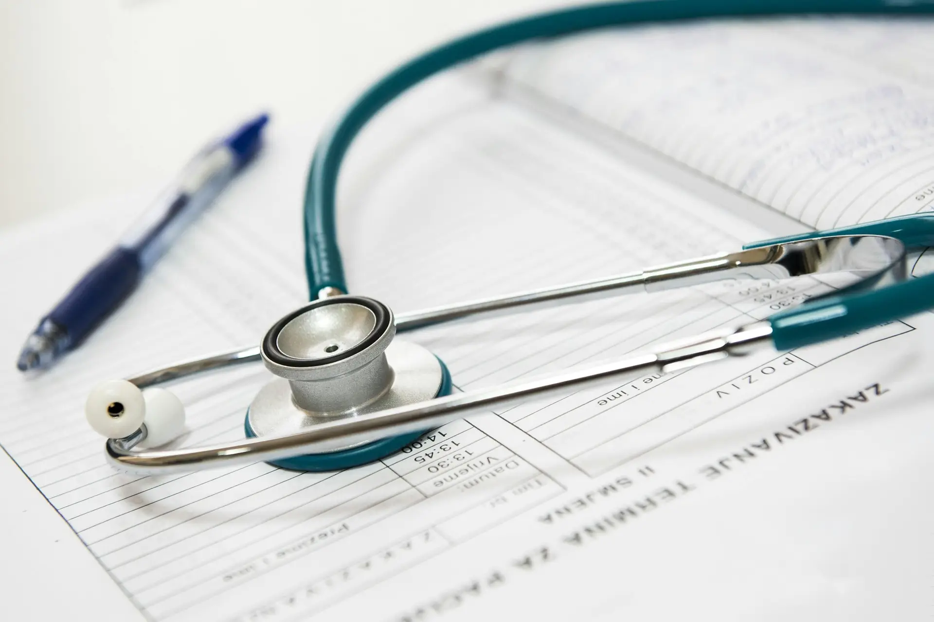 A Stethoscope on a doctor's notebook. There's also a pen near it.