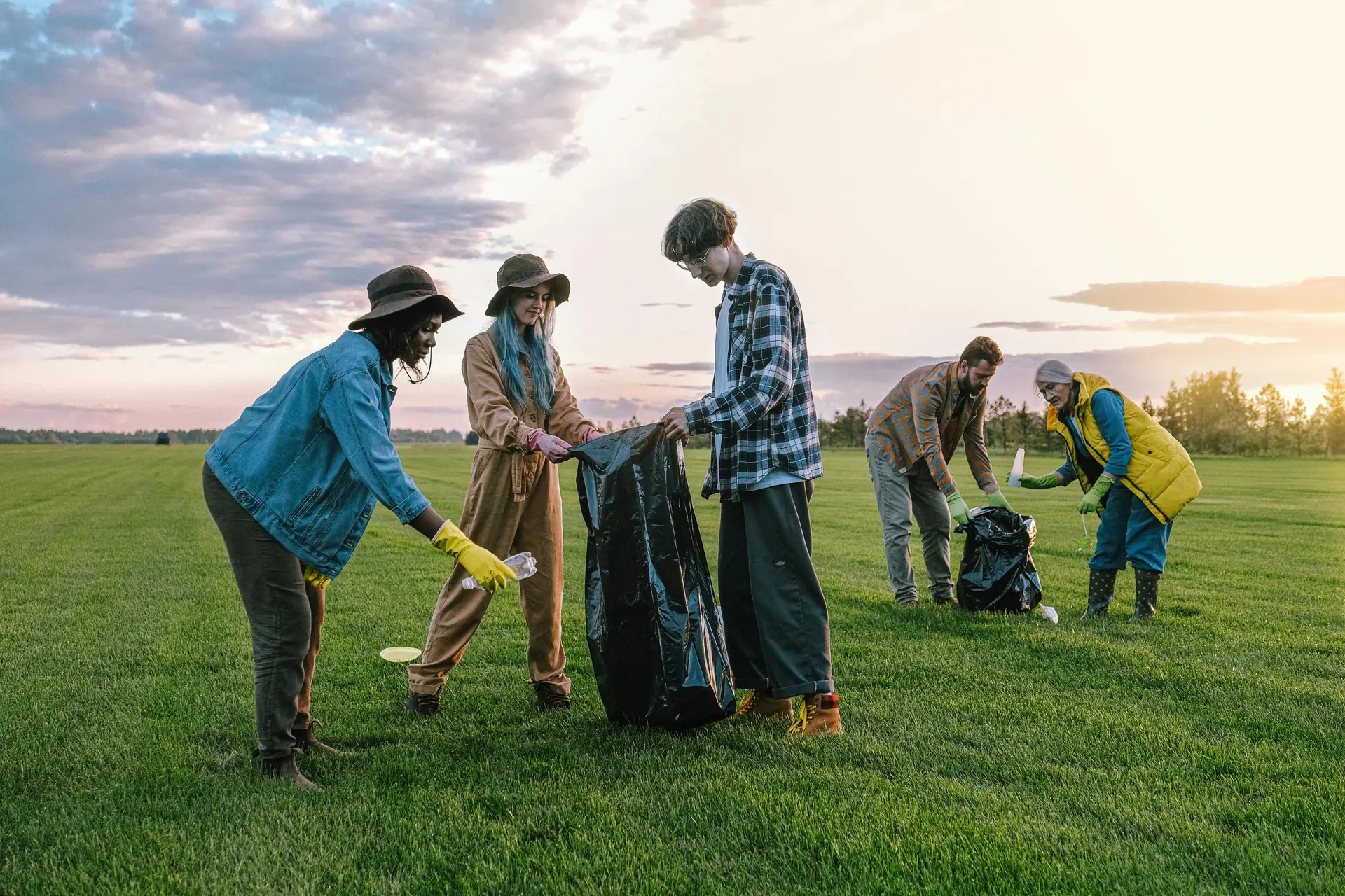 Young volunteers working along with adults to clean up a field.