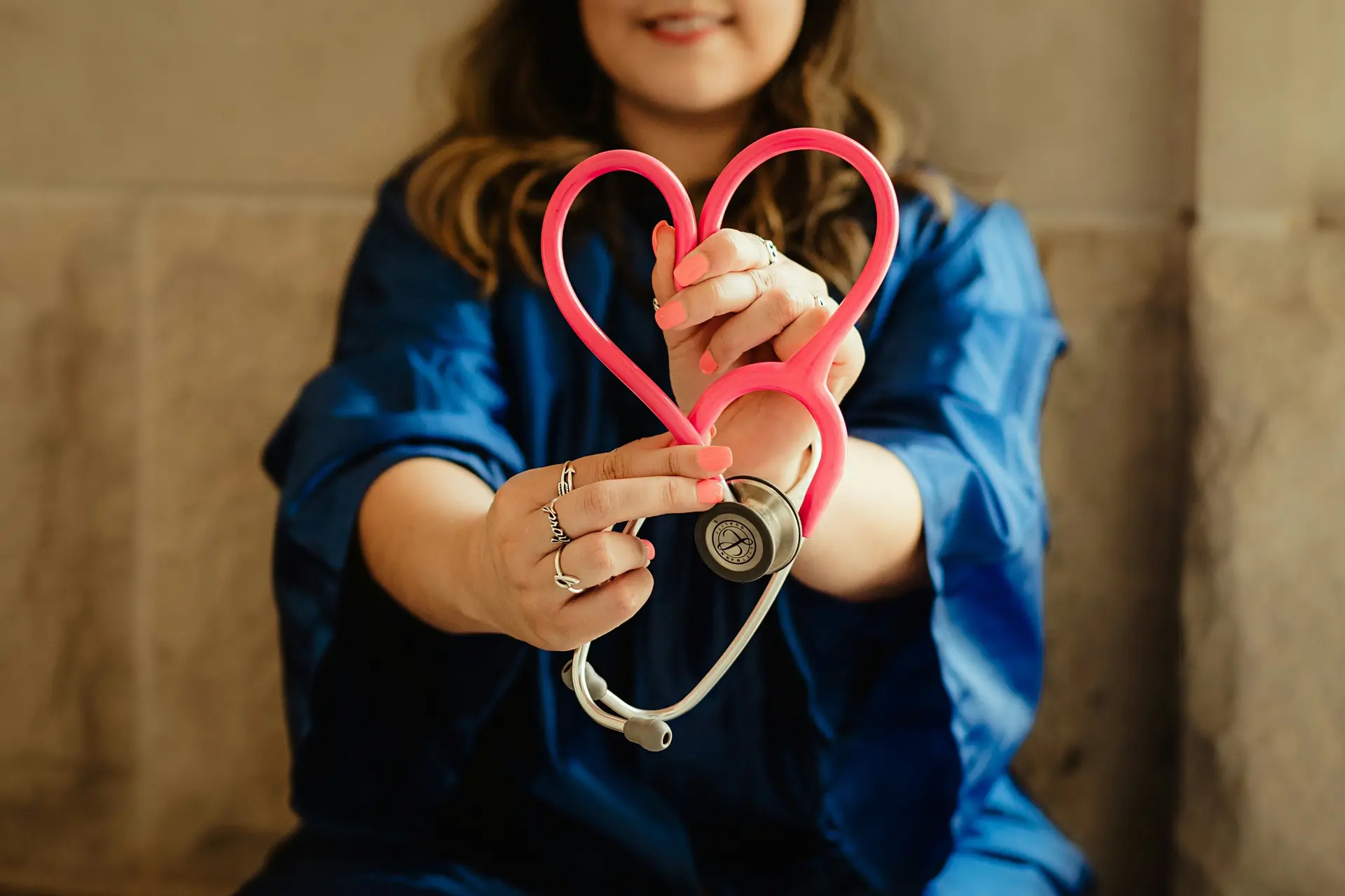 A nurse making a heart shape with their stethoscope.