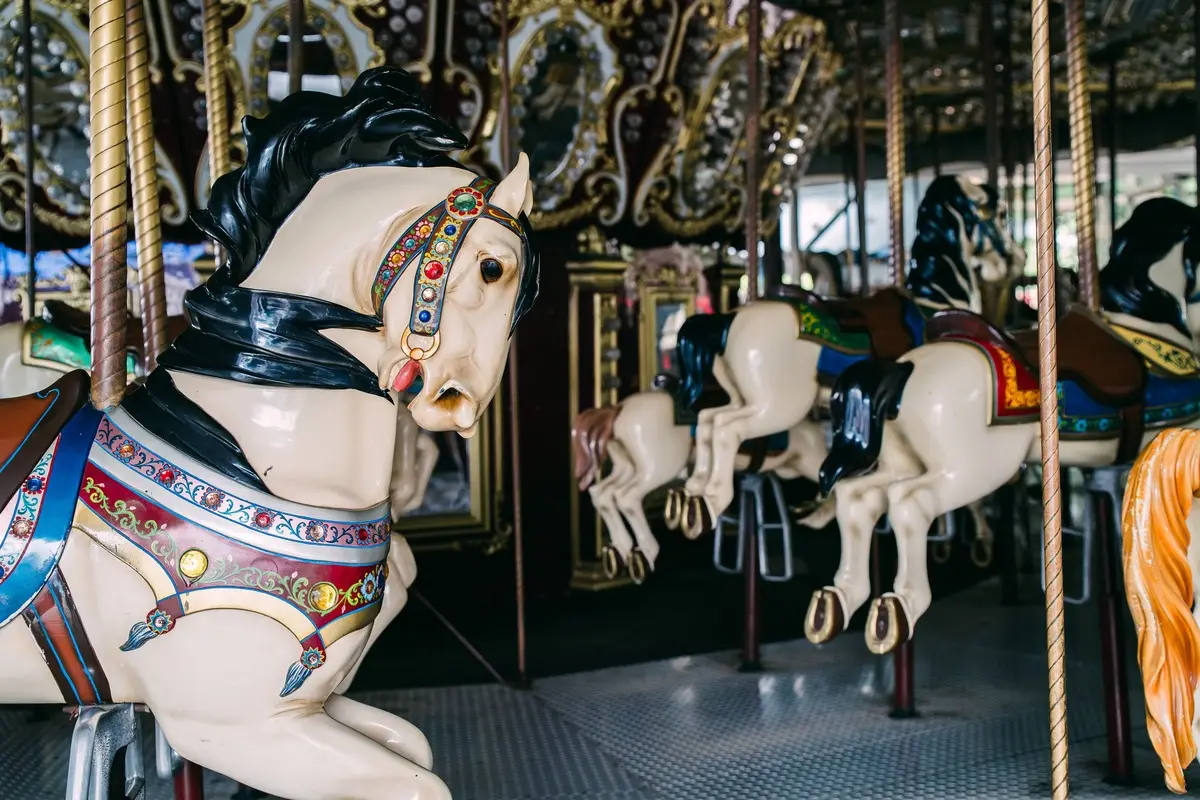 Vintage carousel horses with intricate details at a fairground.