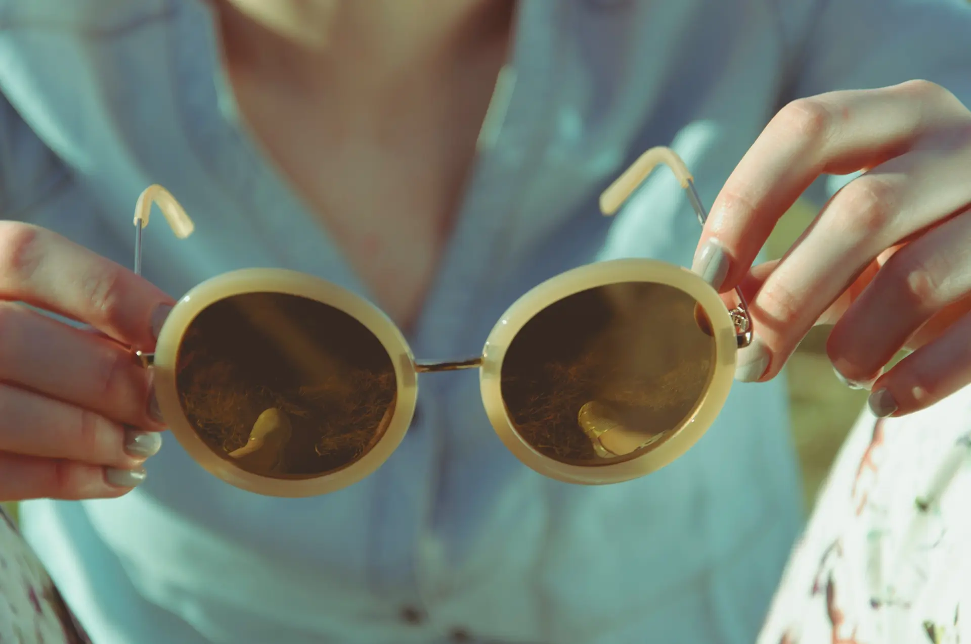 A person holding a pair of sunglass in their hands.