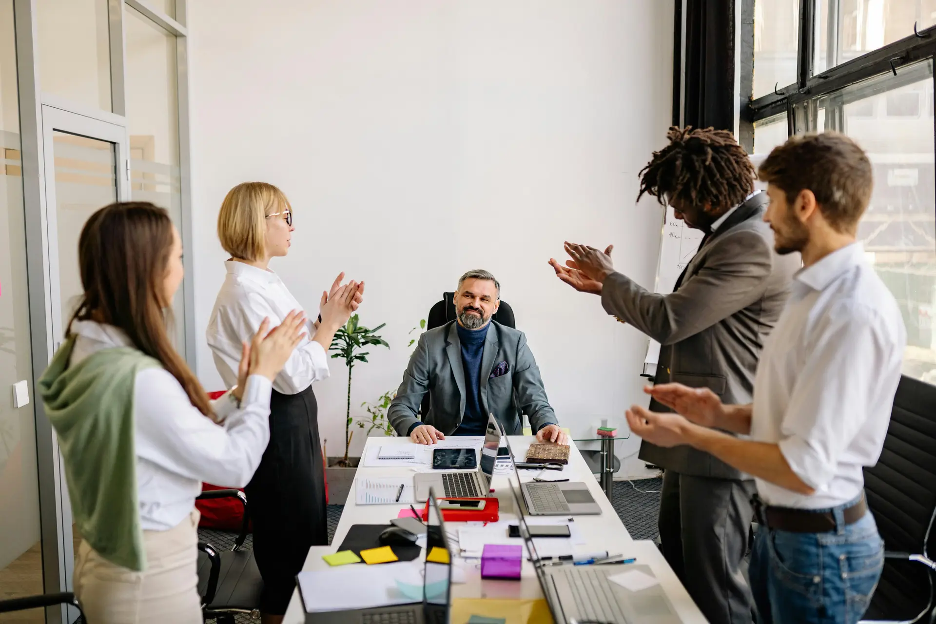 A office team standing up and applauding their boss who is sitting down.