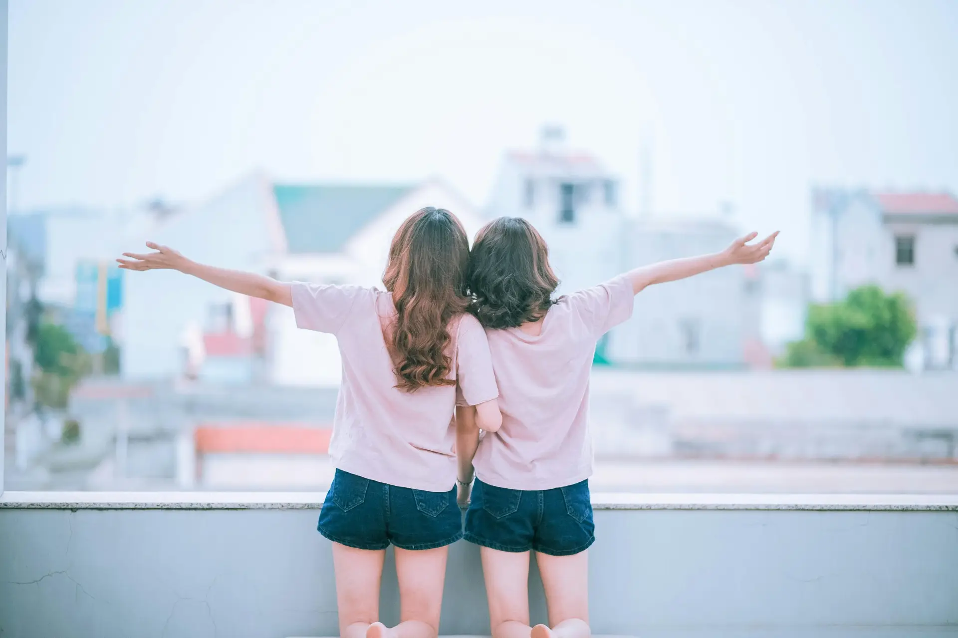 Two sisters holding each other on a balcony.