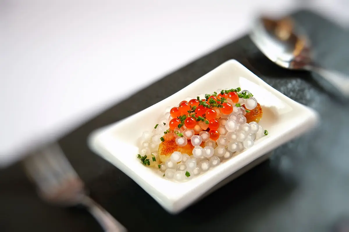 Luxurious gourmet caviar dish served on a small plate with artistic presentation in fine dining setting.