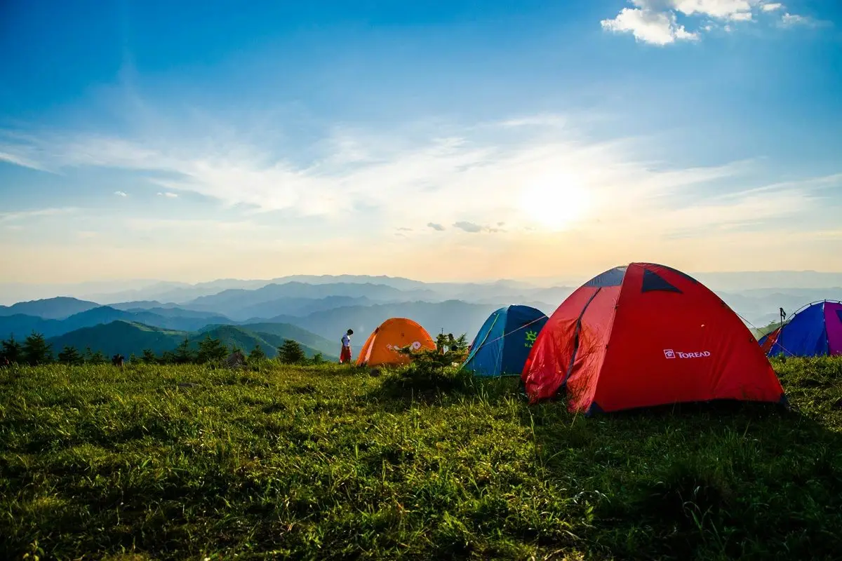 Four pitched dome tents overlooking mountain ranges.