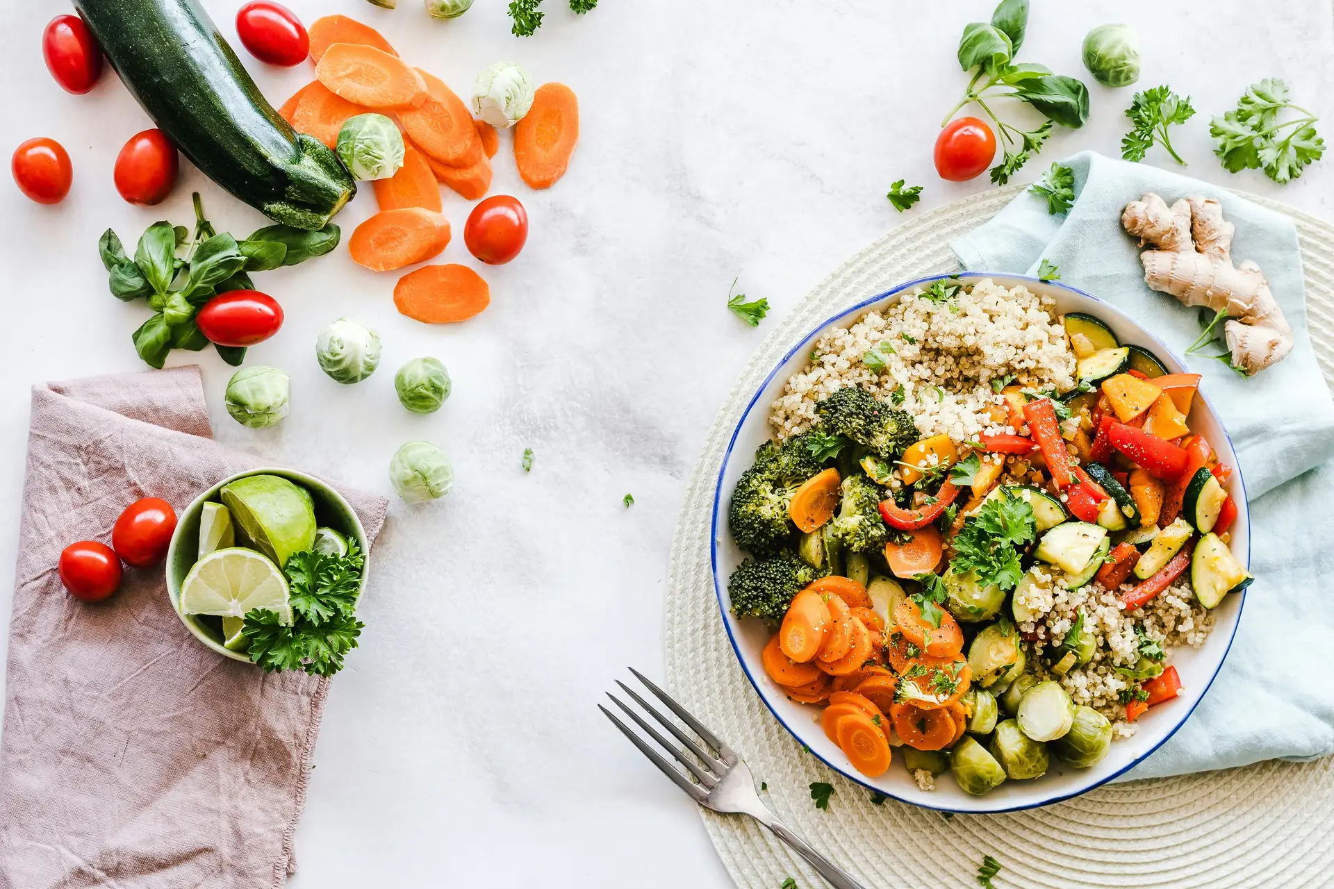A bowl full of cooked vegetables next to some uncooked ones.