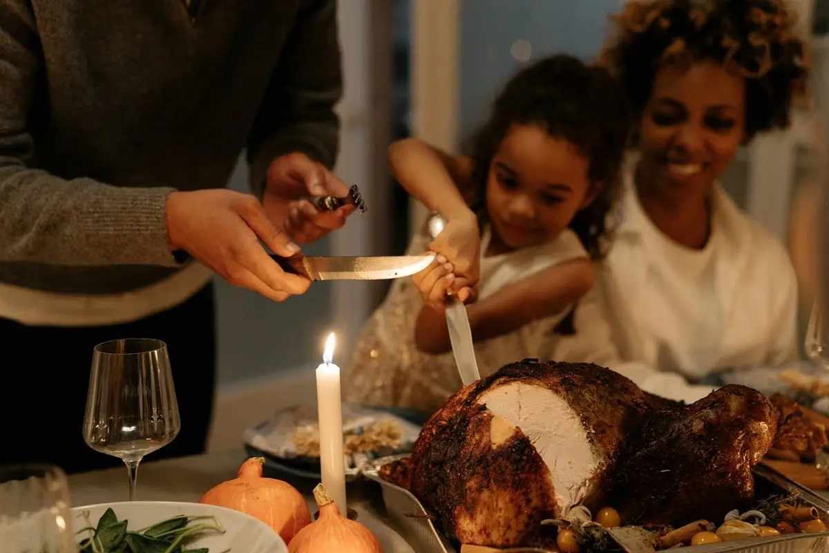 A kid slicing a turkey on a Thanksgivings dinner.