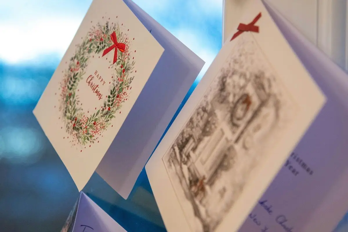 Two white colored Christmas cards along with wreath is on display.
