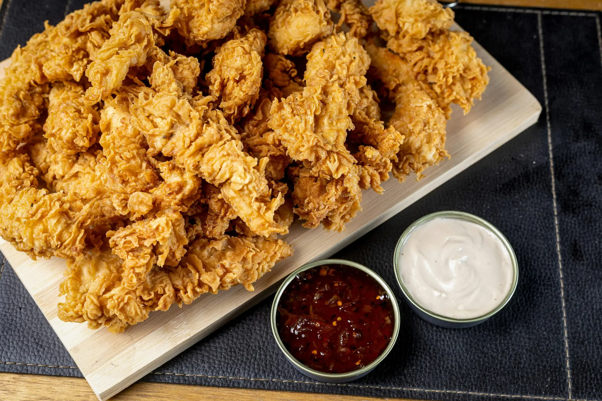 Crispy fried chickens on a platter along with dips and sauce.