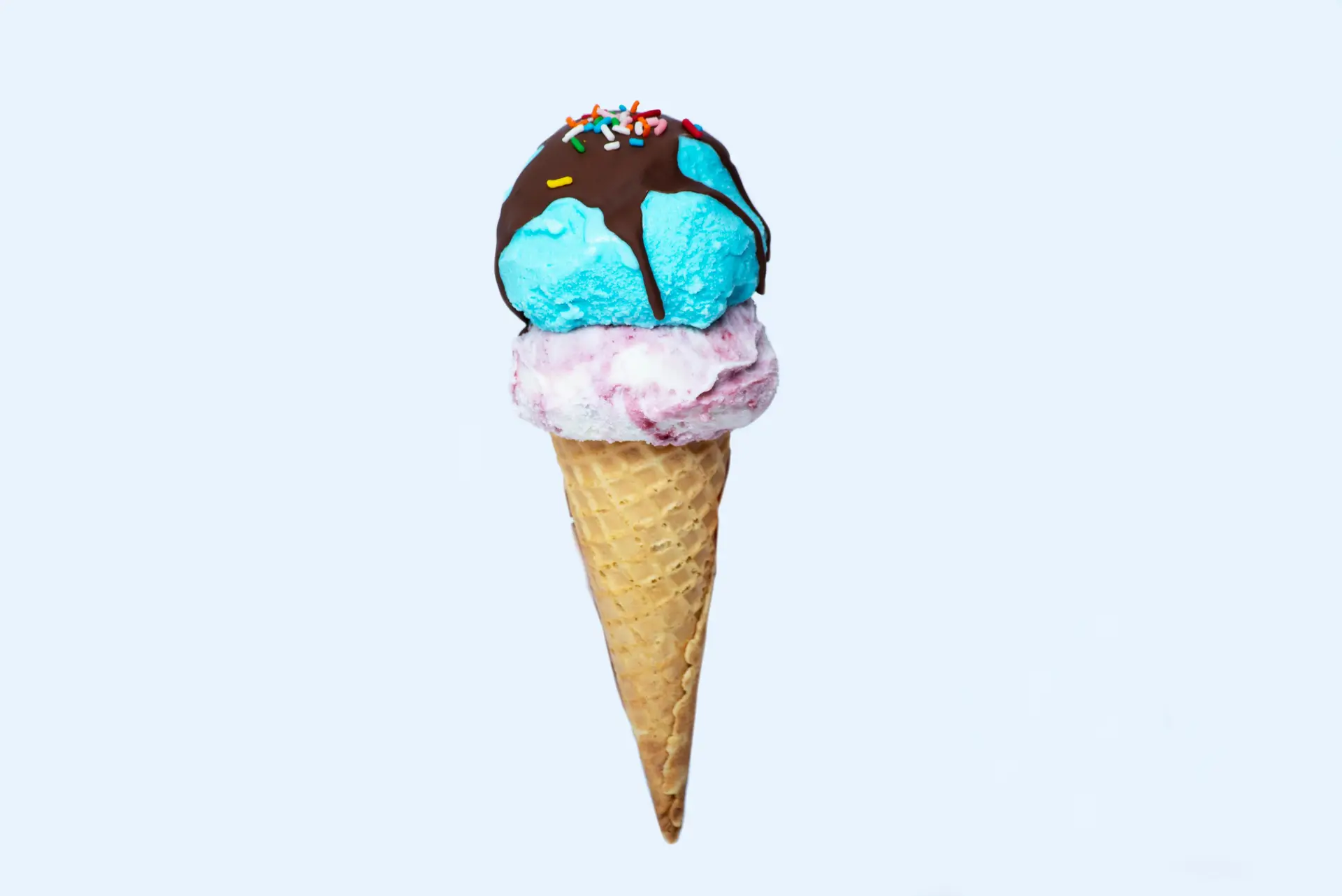 Double scoop ice cream cone with chocolate syrup and sprinklers on top.
