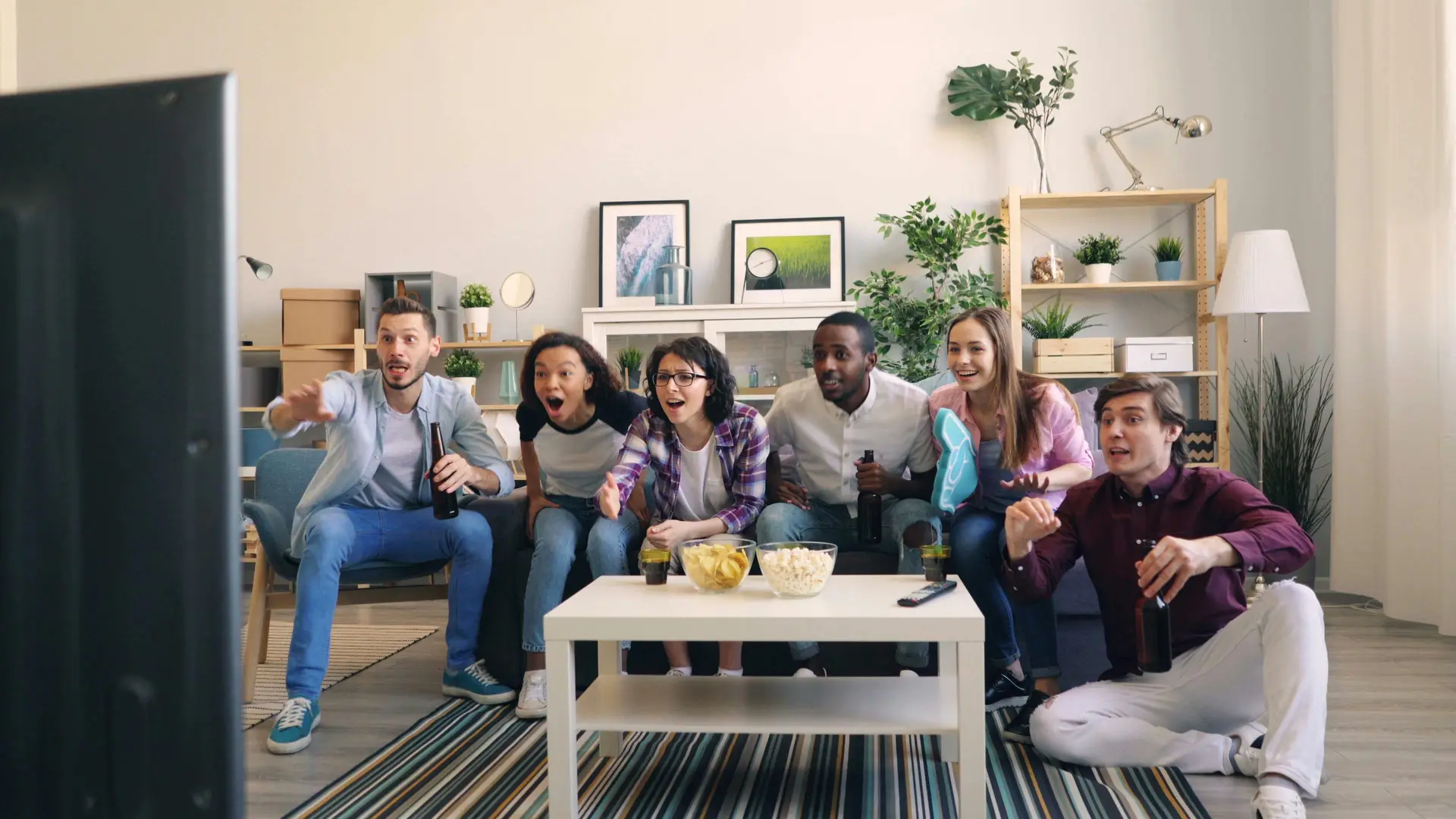 Group of friends enjoying American football on National Football Day by watching match on TV.