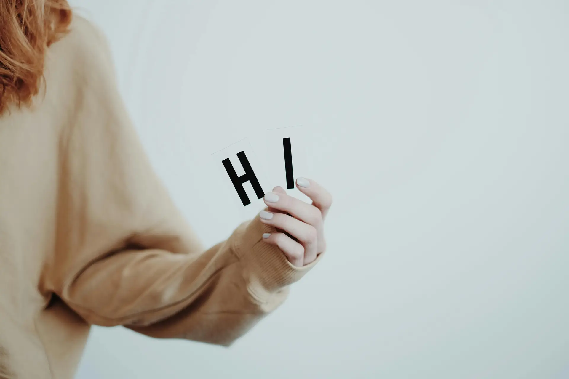 A person holding the alphabets H and I, which spells out Hi.
