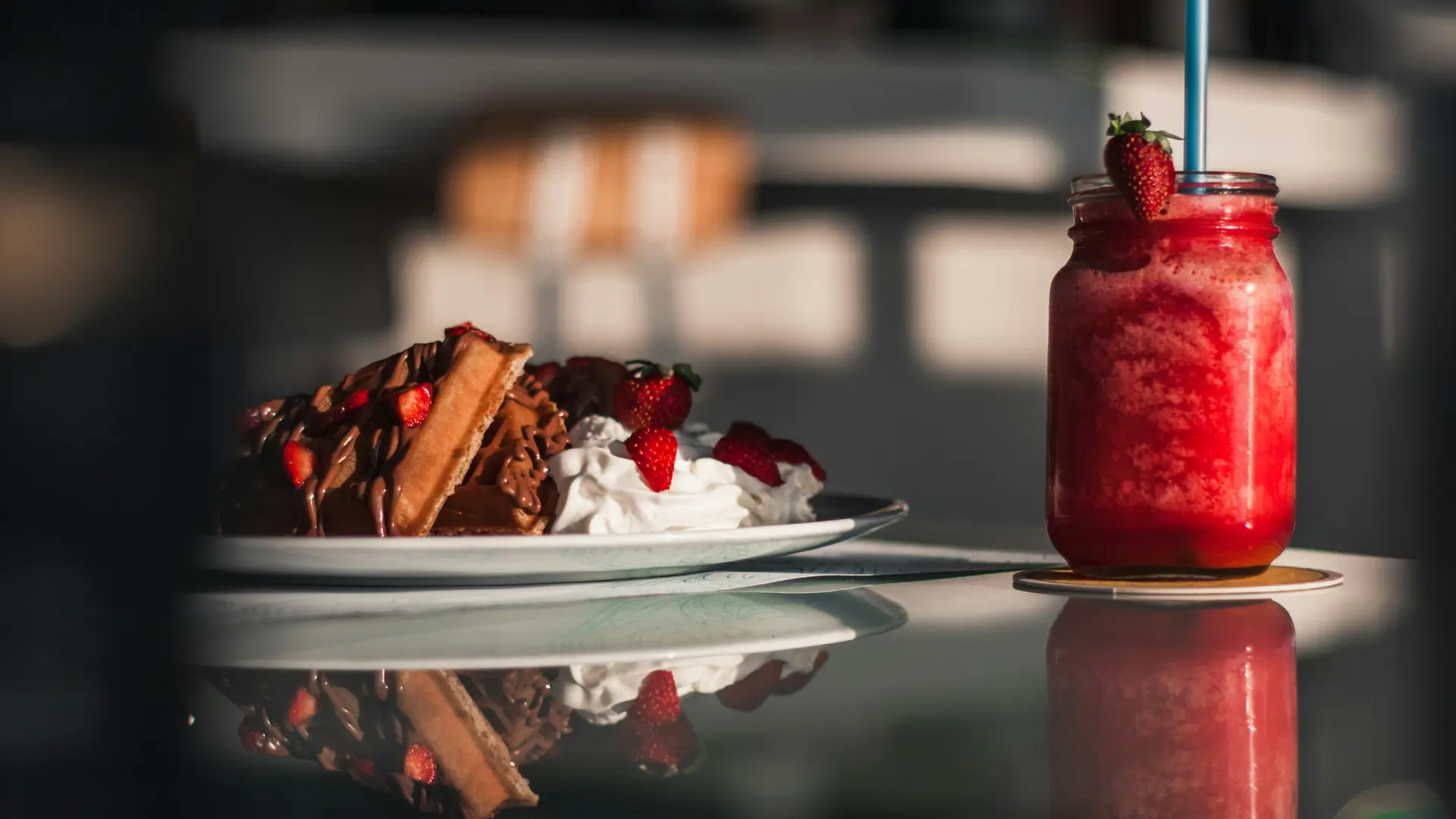Chocolate Waffles with strawberry and ice cream served on a plate with a strawberry drink on the side.