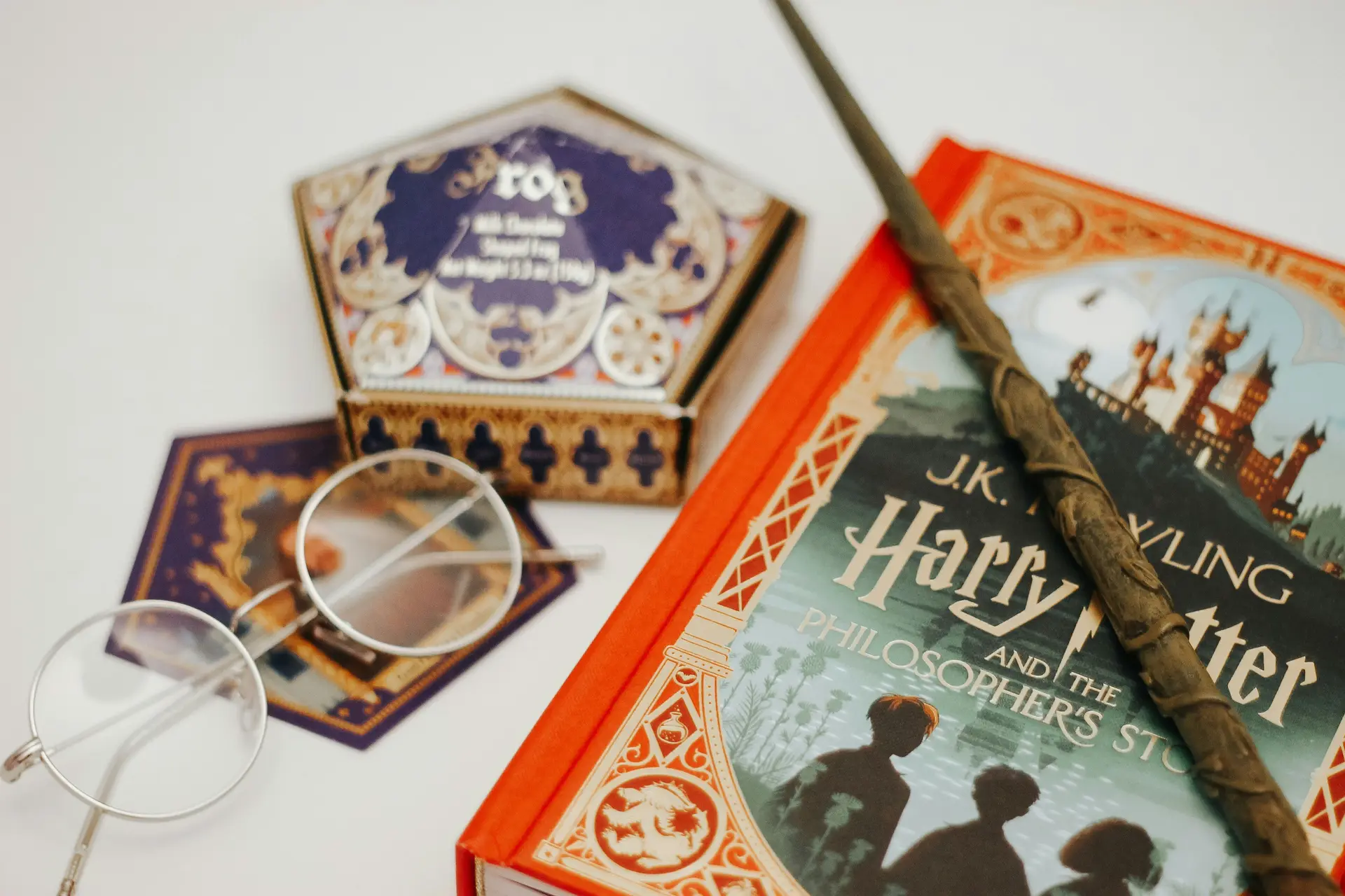 Harry potter book with accessories including a want, a box of chocolate, harry potter's glass, etc.