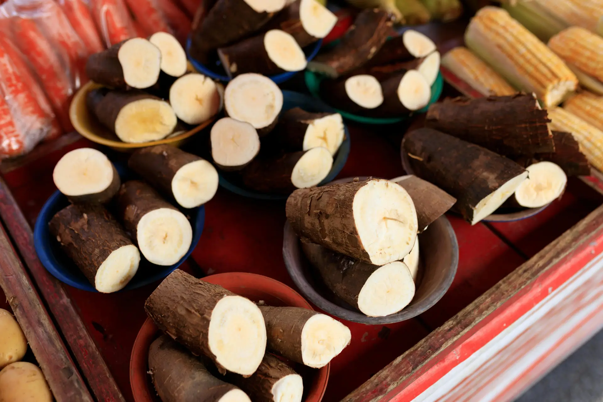 The roots of cassava plants are displayed in little bowls on a table at a market.
