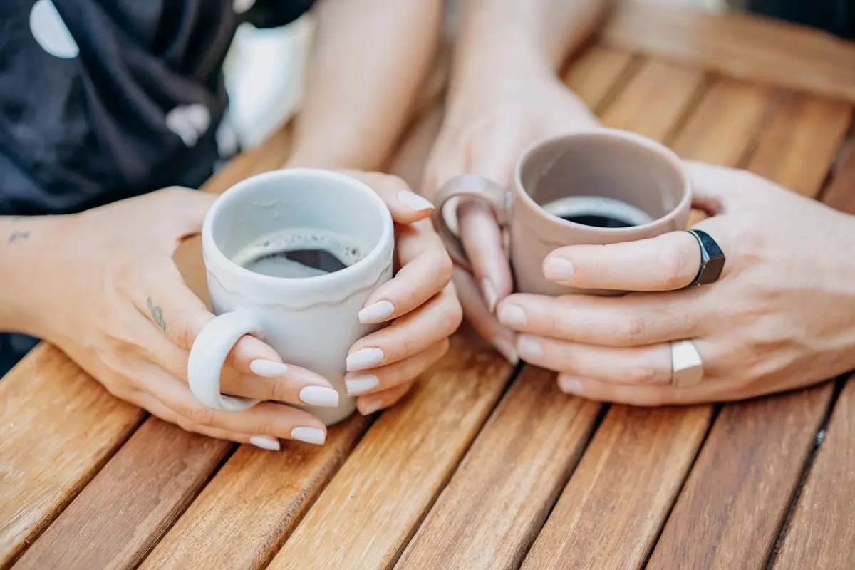 Two person holding two cups of espresso.