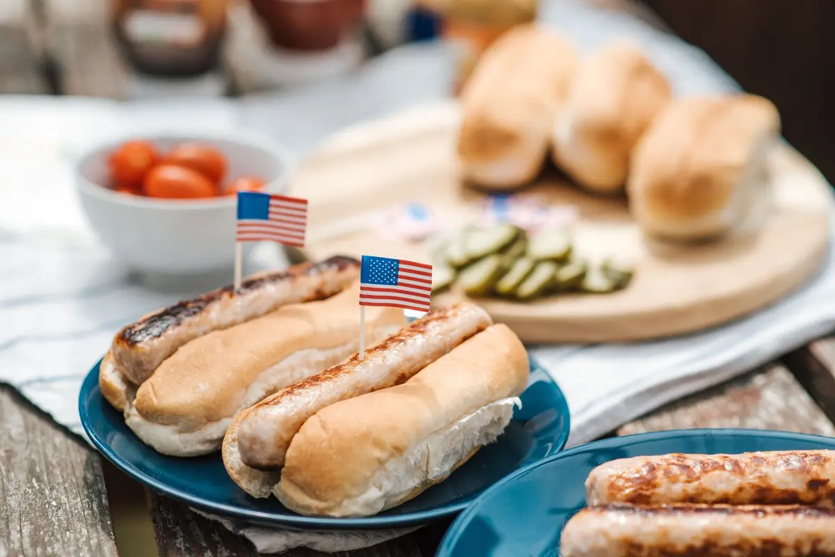 Hot dogs with American flags on a plate, perfect for a Fourth of July celebration.