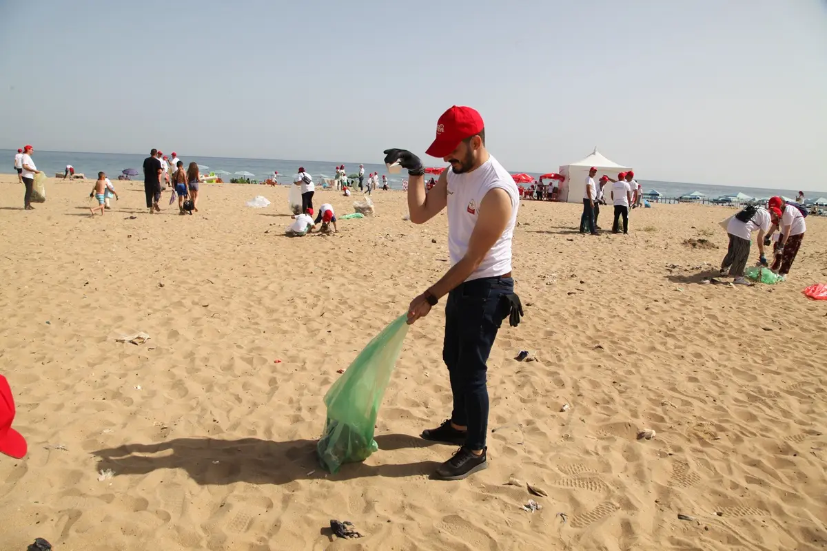 Volunteers cleaning up beach in Algiers, promoting environmental awareness.