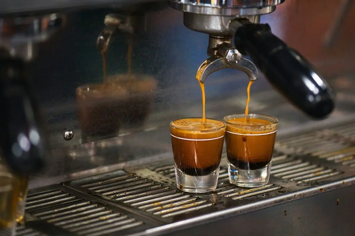 An espresso machine pouring two shots of Espresso into shot glasses.