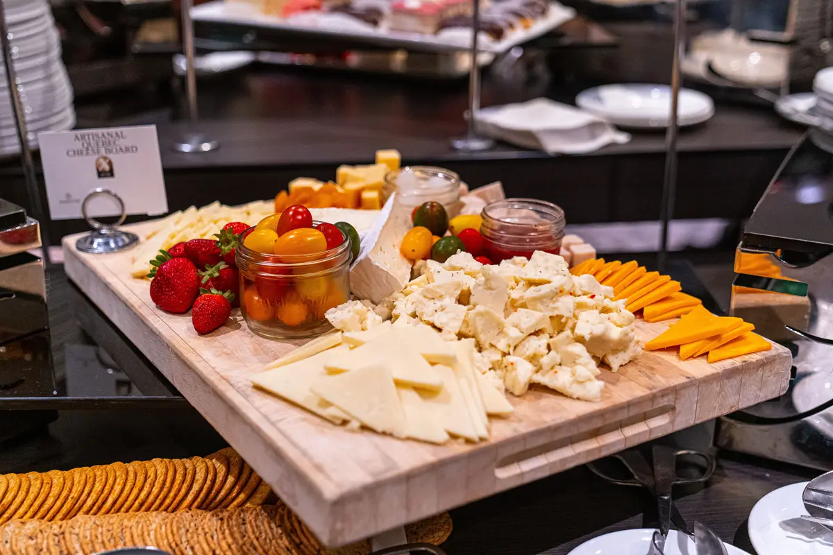 A gourmet artisanal cheese board featuring assorted cheeses, fruits, and crackers in an elegant indoor setting.