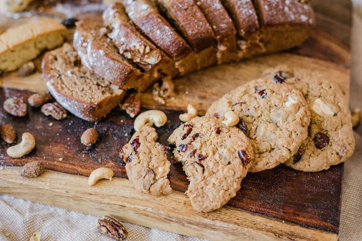 Assorted baked goods, including breads and cookies, on a rustic wooden tray.
