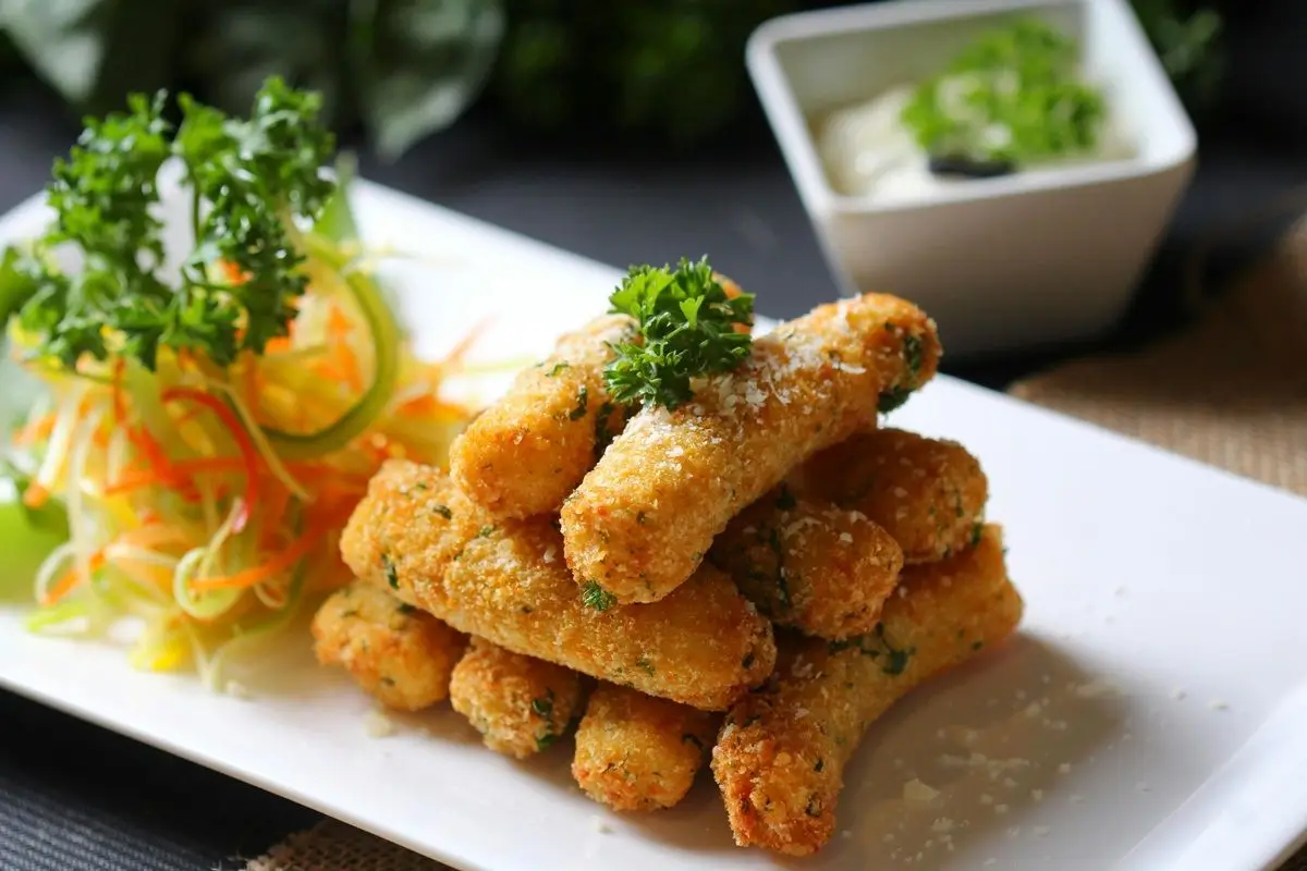 Fried cheese curds on a ceramic plate with some vegetables.