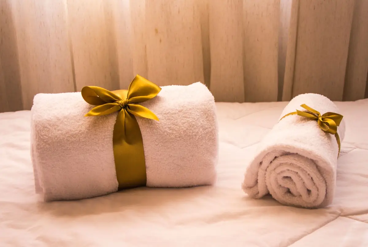 Luxurious white towels adorned with golden ribbons on a bed, creating an elegant and welcoming atmosphere.