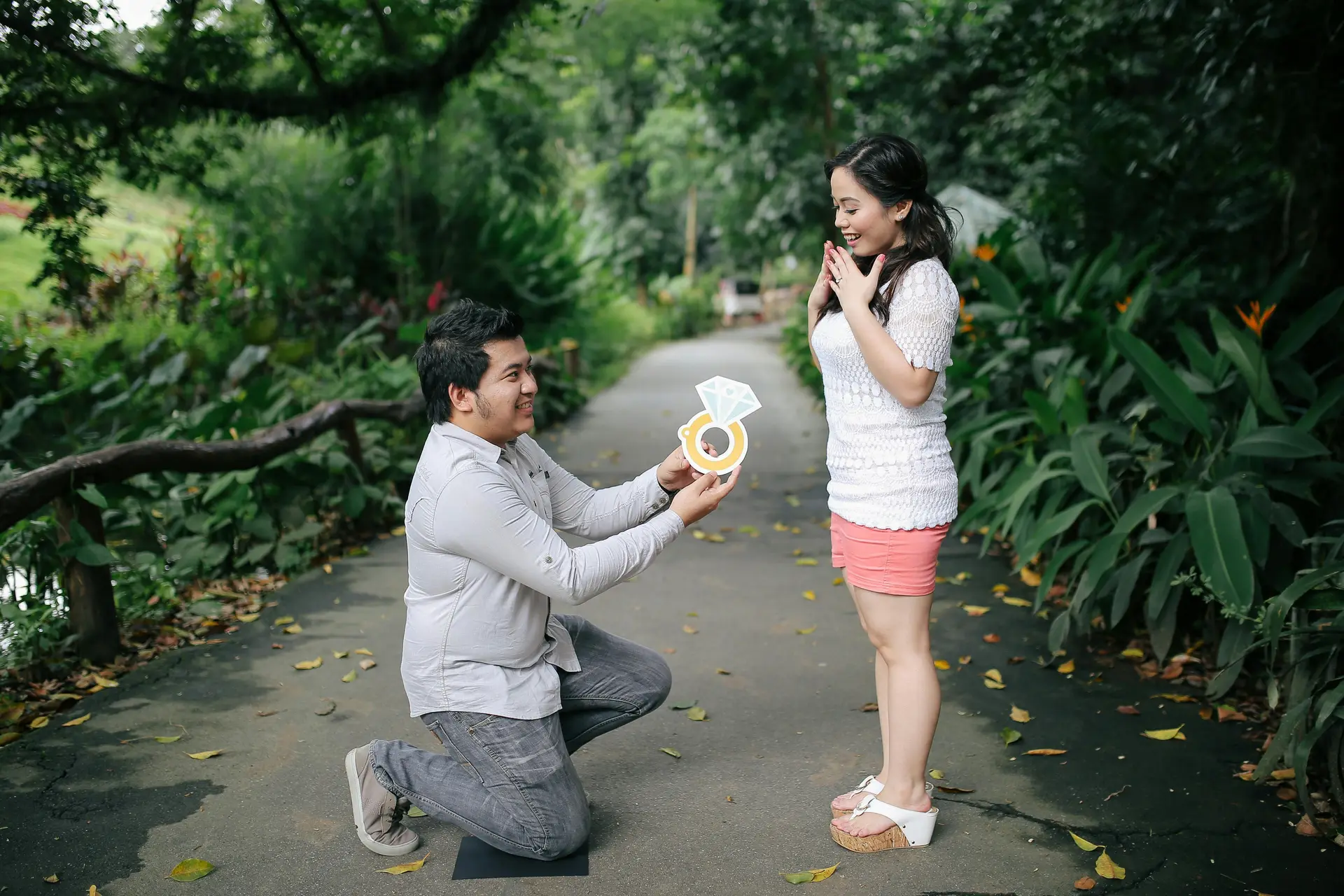 Man proposing with a ring cutout in a place surrounded by greenery.