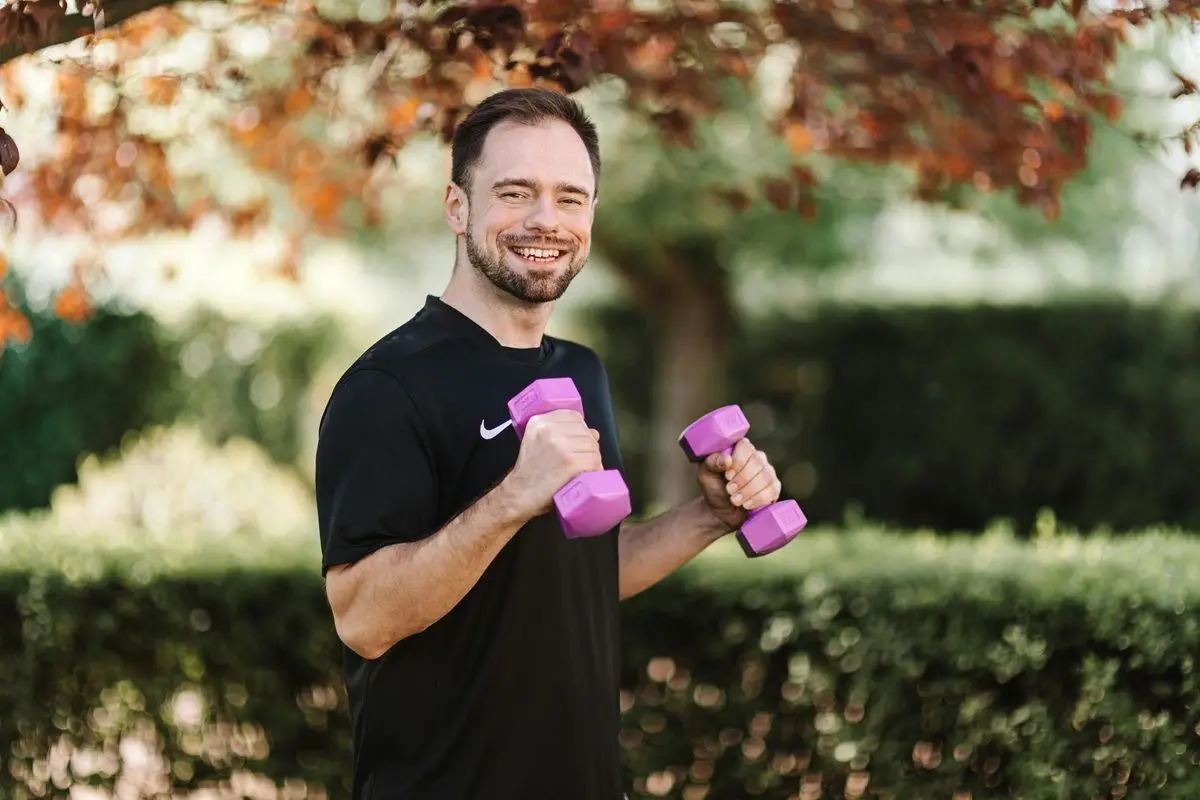 A man laughing while exercising with dumbbells.