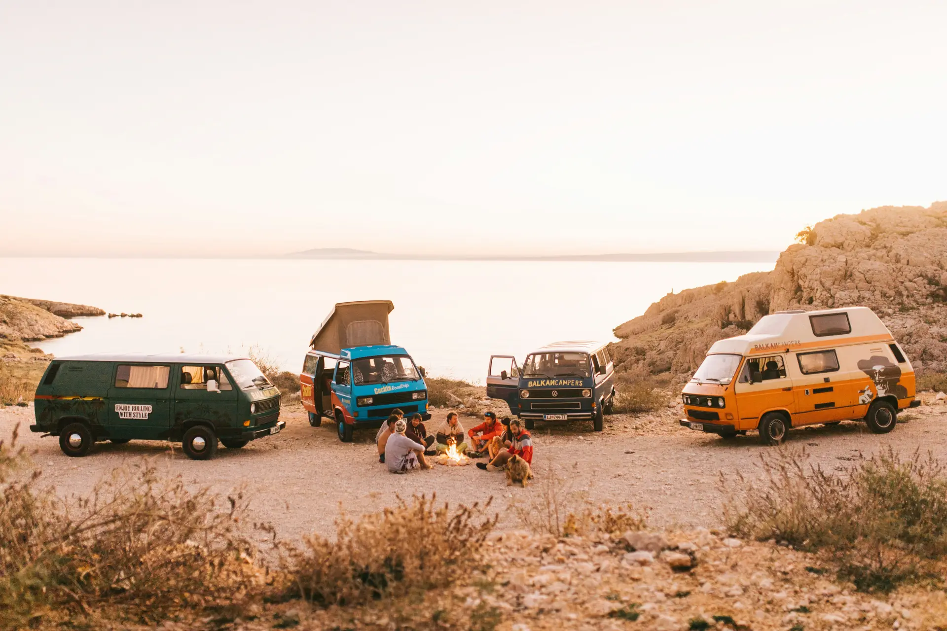 Bunch of people camping from of four parked cars that have camps on them.