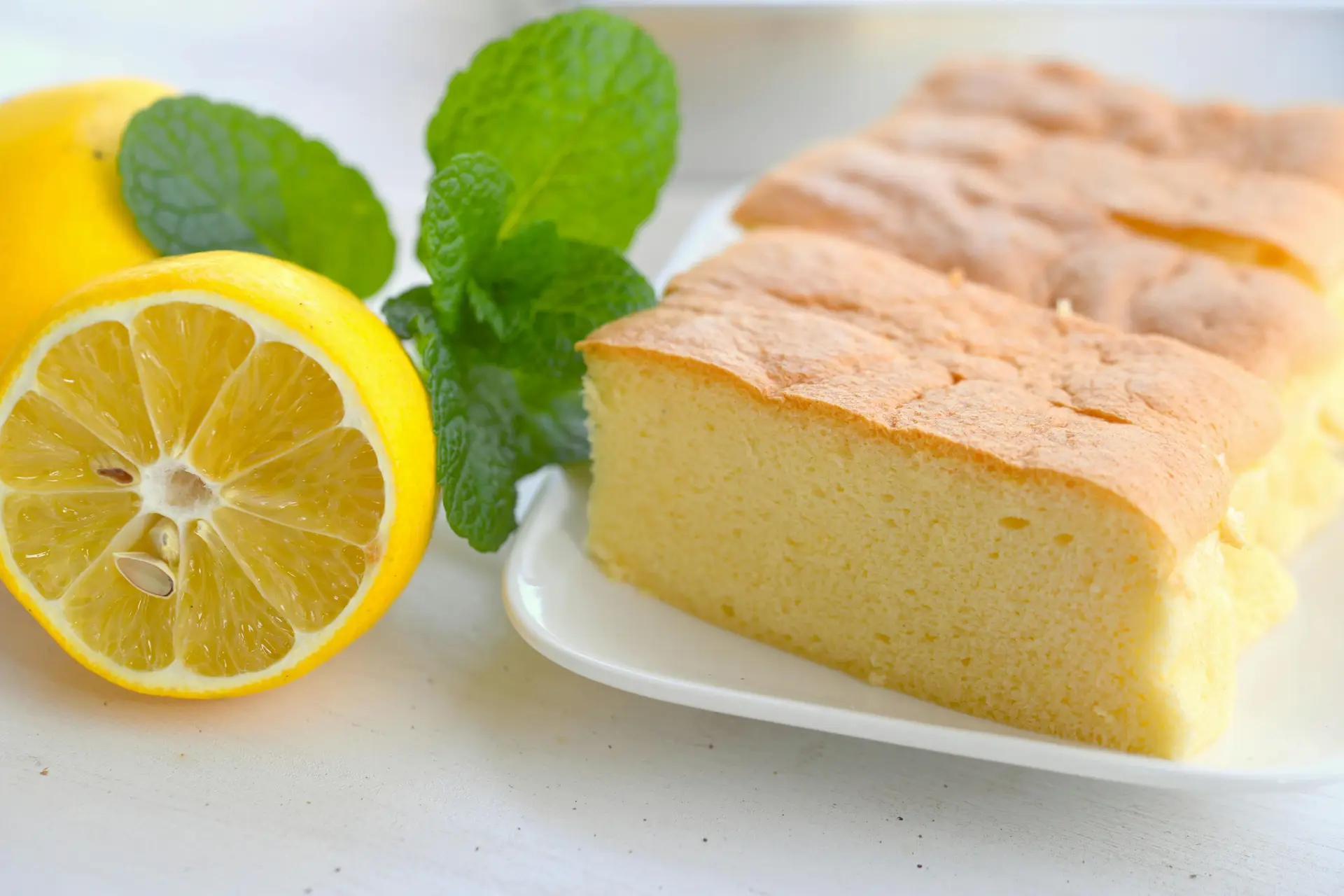 Classic sponge cake decorated with mint leaves and lemon on National Sponge Cake Day.