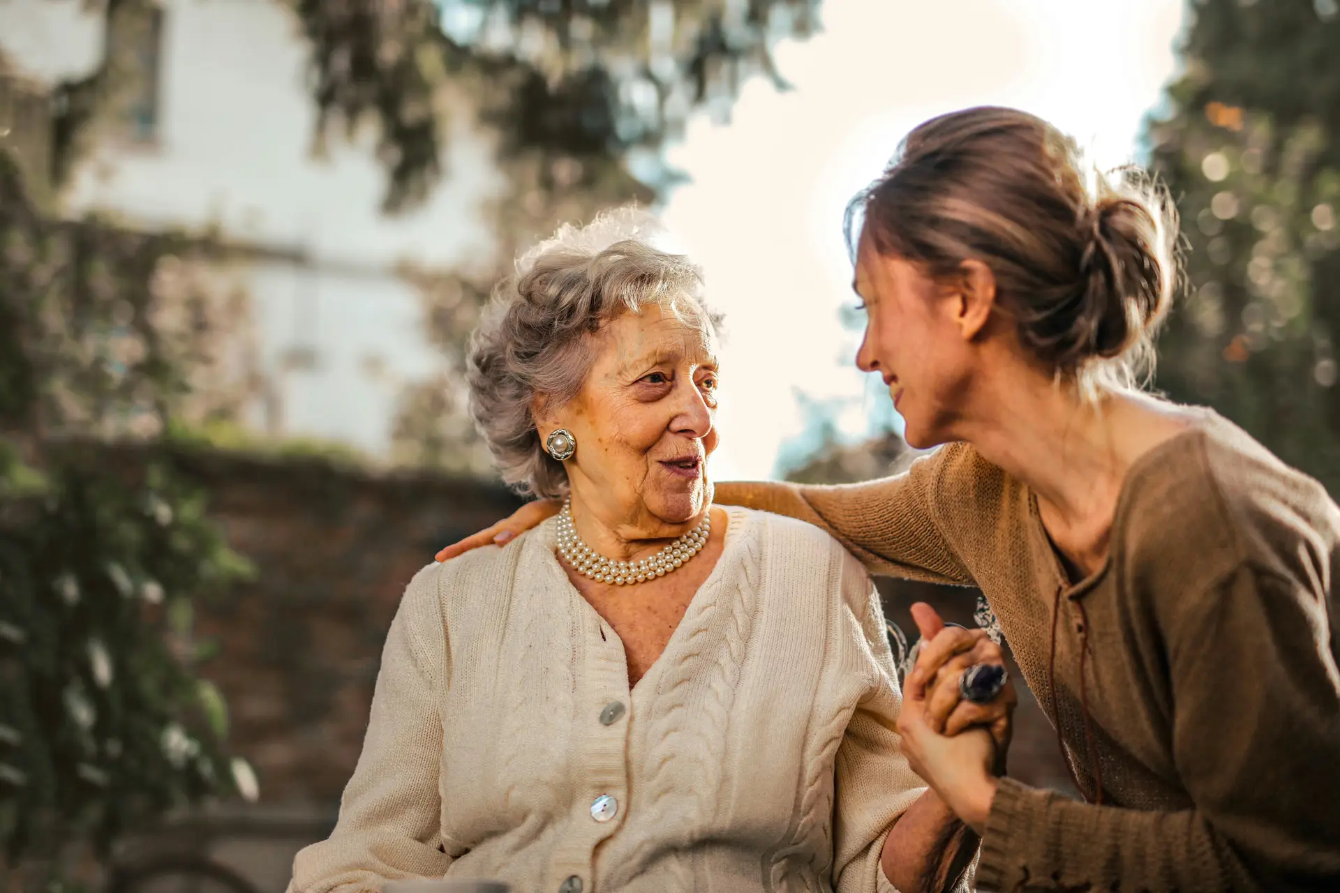 A young woman embracing her old neighbor.