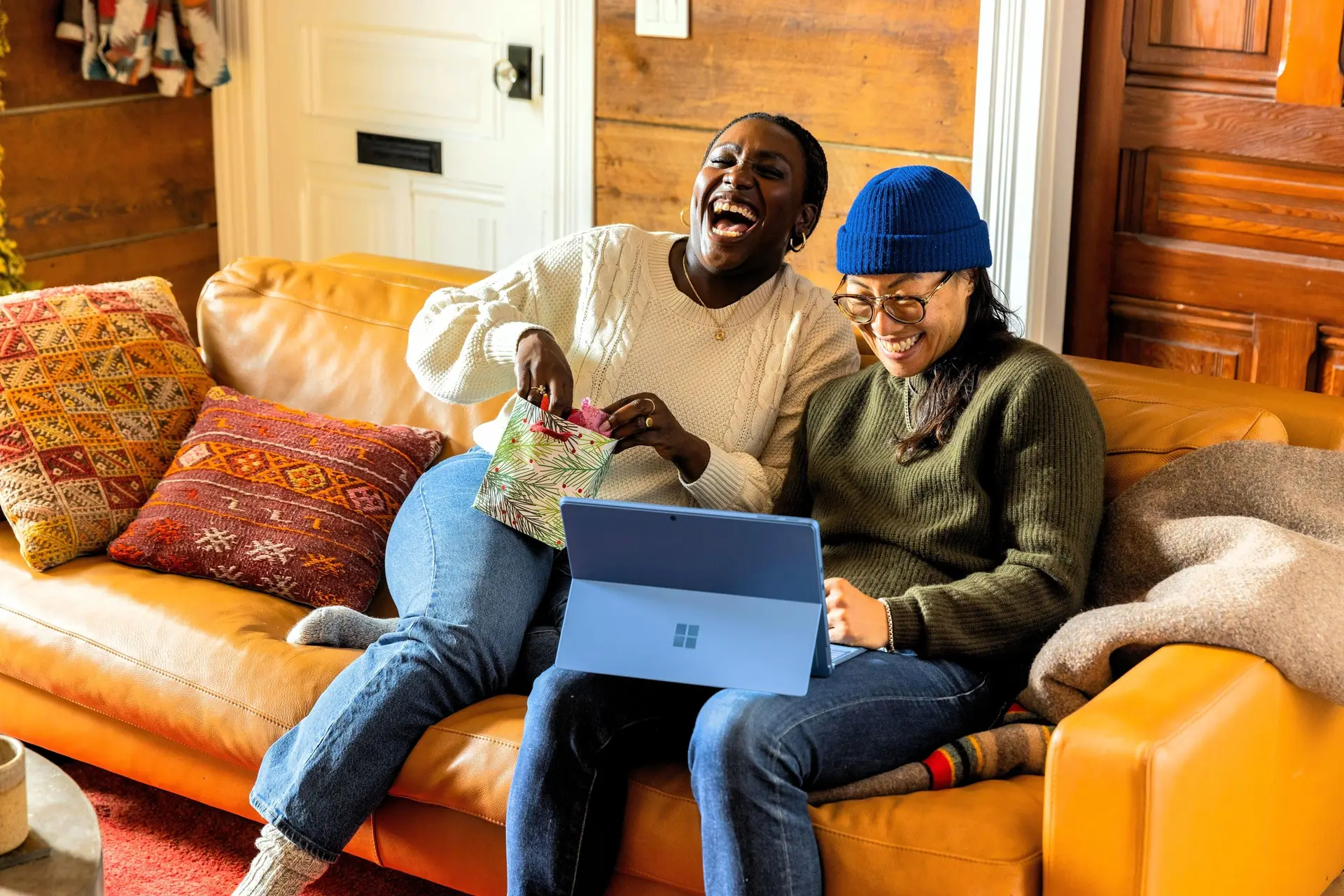 Two women laughing while watching something on a laptop.