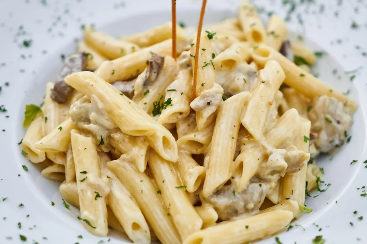 Creamy cheese pasta on a plate garnished with some thime.