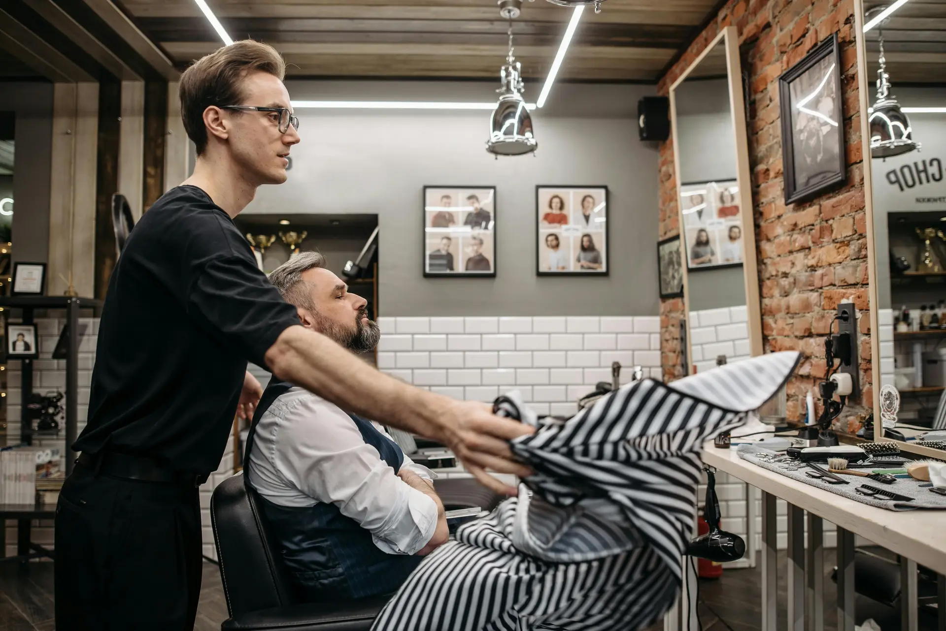 A hairstylist placing cape on a client.
