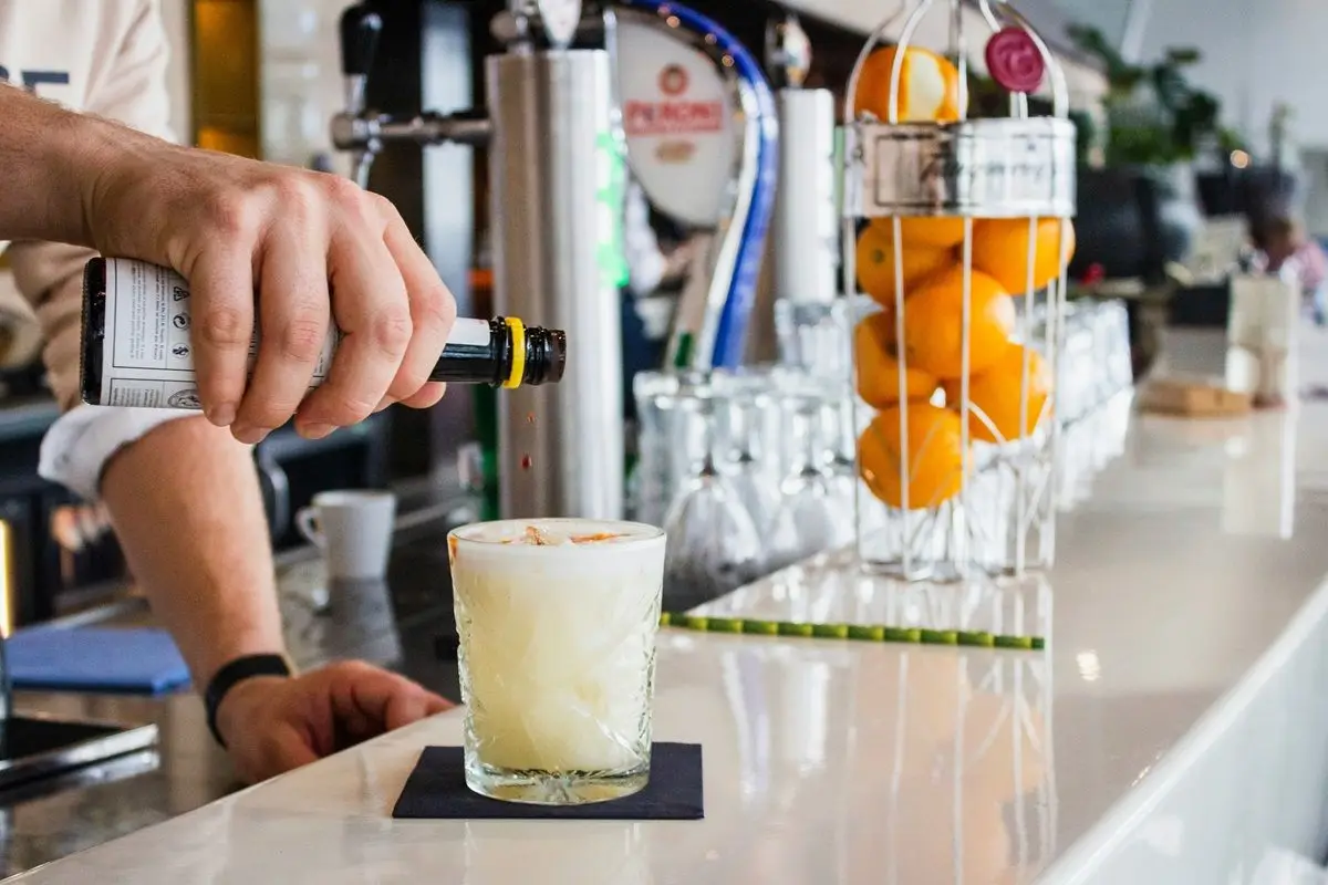A person pouring spirits in a glass of eggnog.