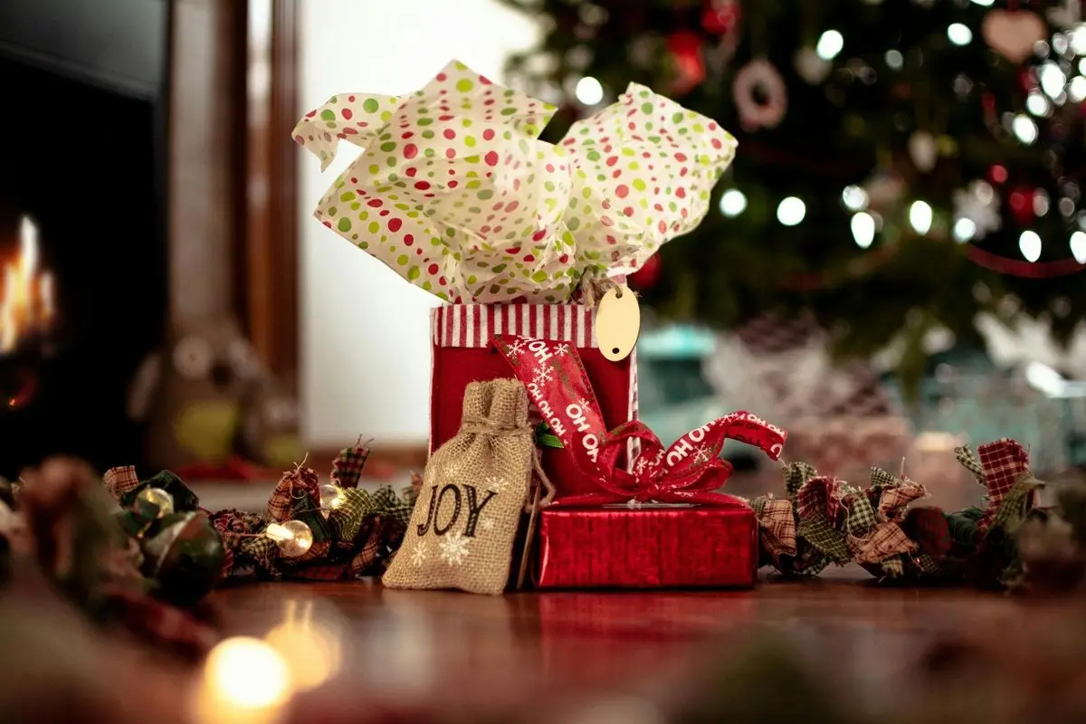 A giftbox wrapped in red gift wrapper placed on a wooden table.