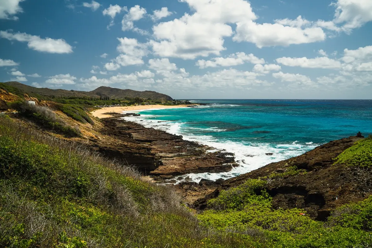 Stunning coastline landscape with vibrant turquoise waters and rocky shore under a clear sky.