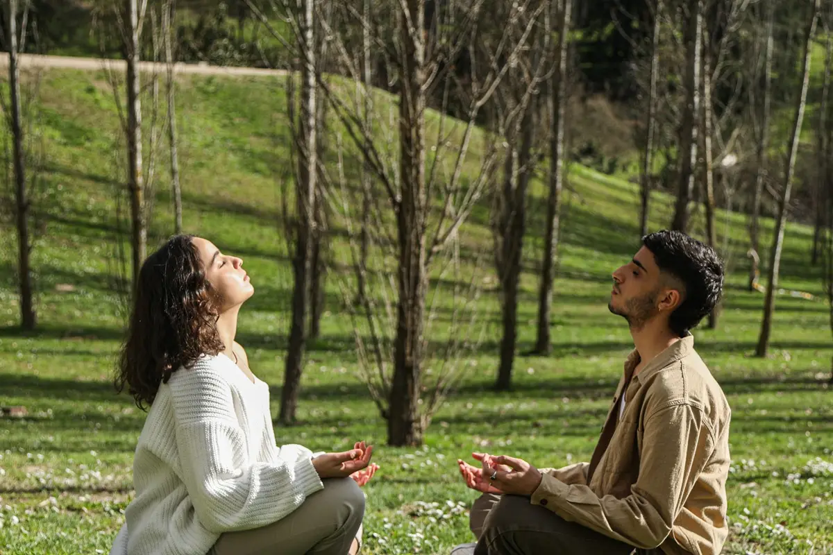 Two adults meditating in a serene park, enjoying peace and relaxation on National Relaxation Day.